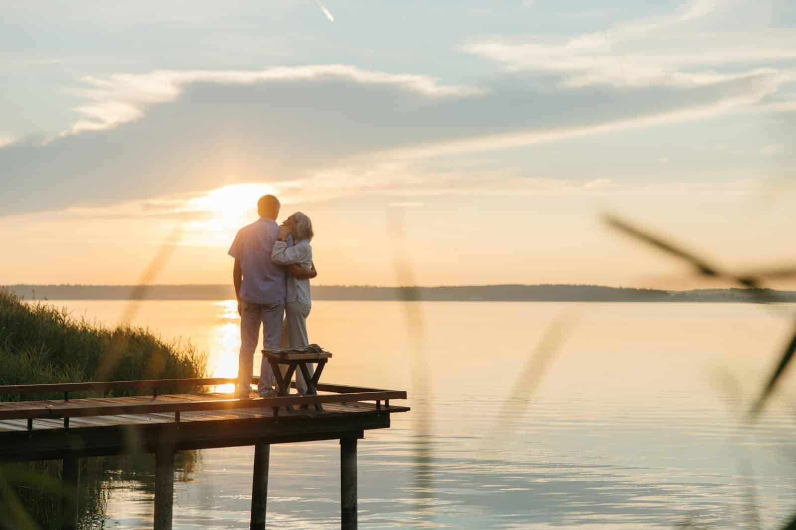 An older couple walking together beside a lake